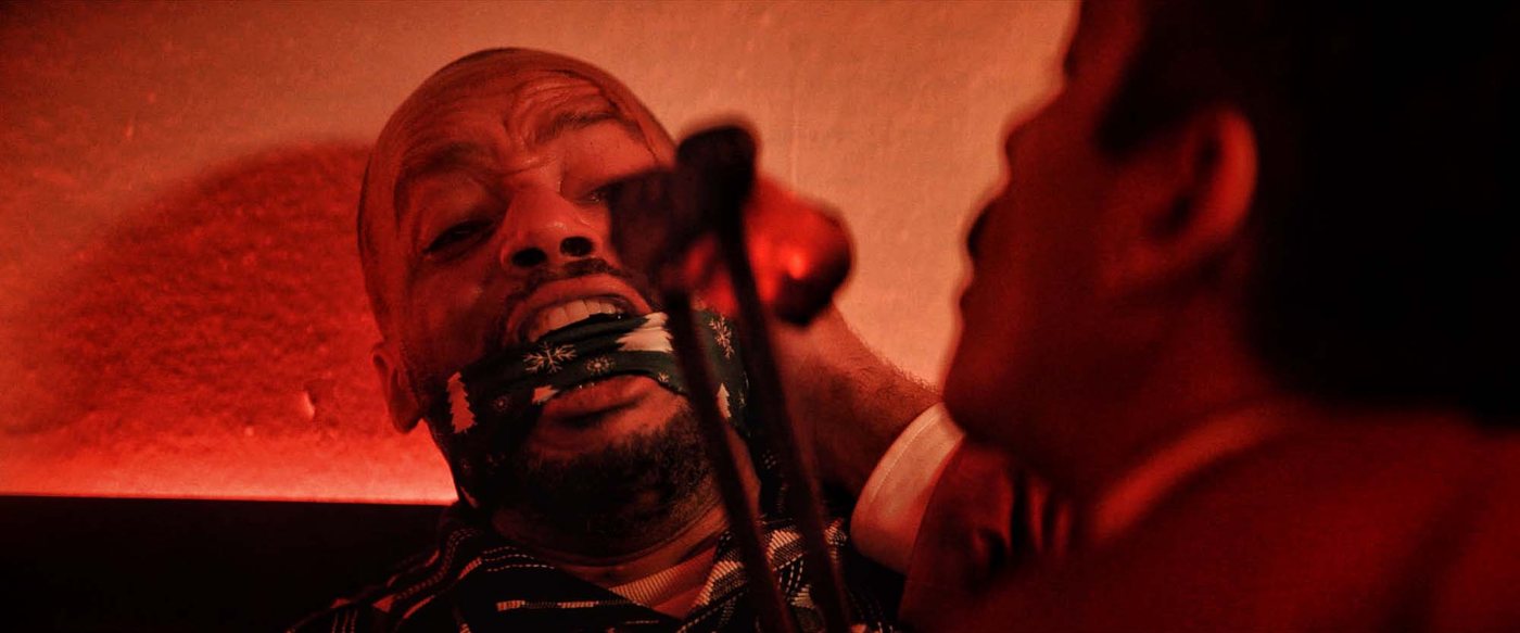 A gagged man lit in red